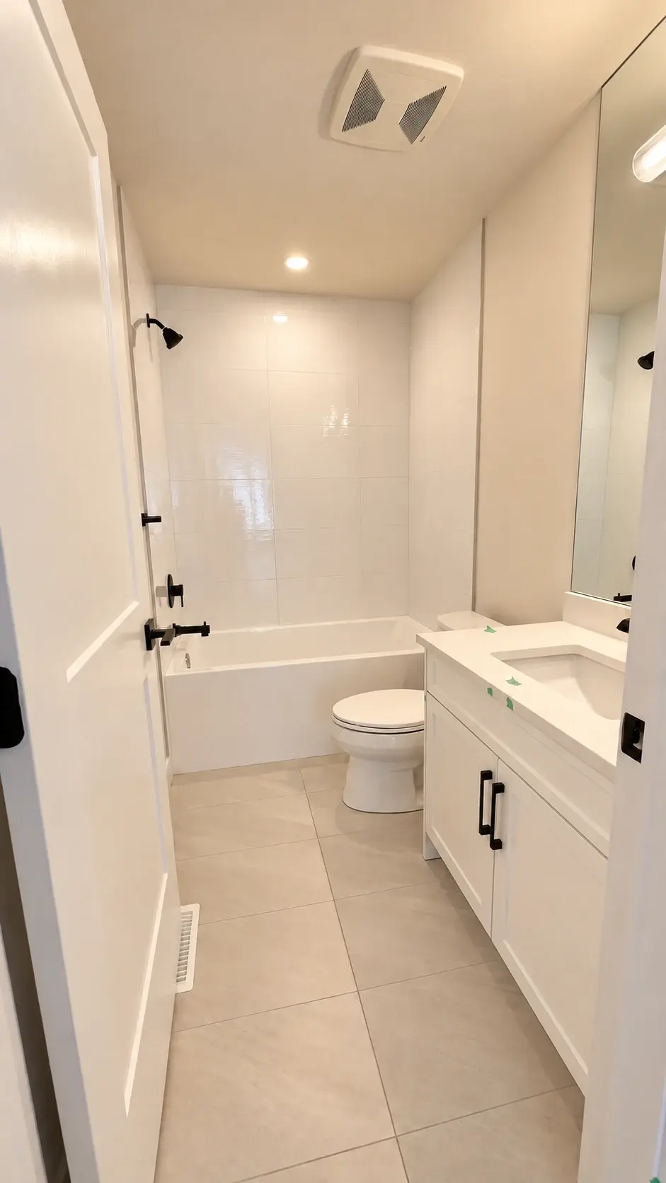 Simple, bright and functional: A light tiled bathroom with a white vanity and recessed lighting.