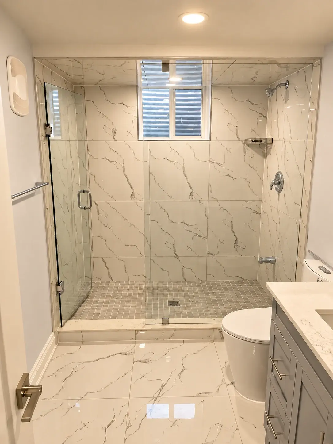 A fresh perspective: Marble-look wall tiles, a recessed niche and a glass shower screen create a crisp bathroom.