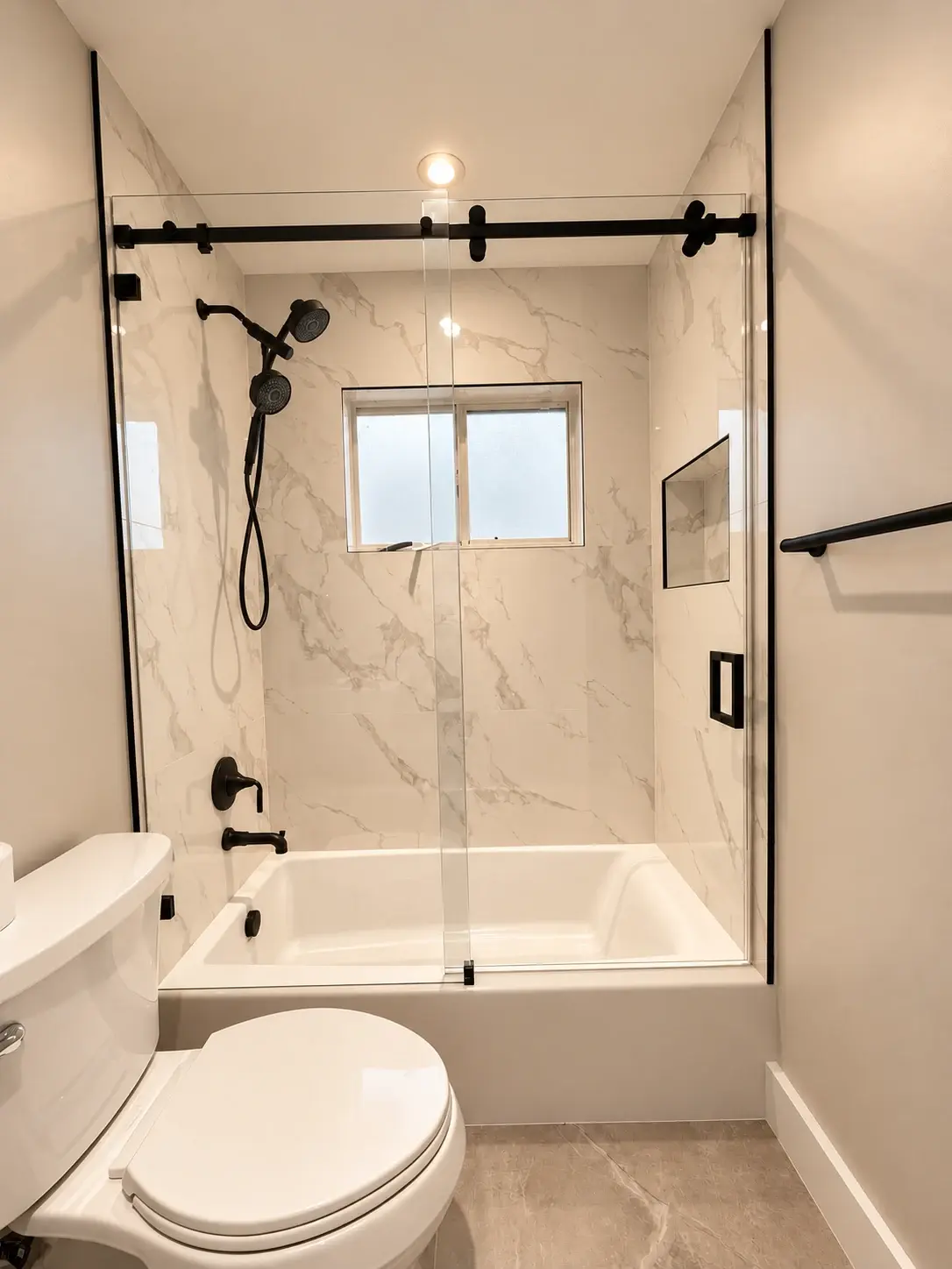 An everyday retreat: A tub with a glass screen, dark shower fittings and light wall tiles make the most of a compact space.